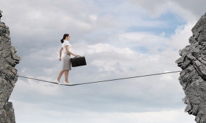 Young confident businesswoman walking on rope above gap