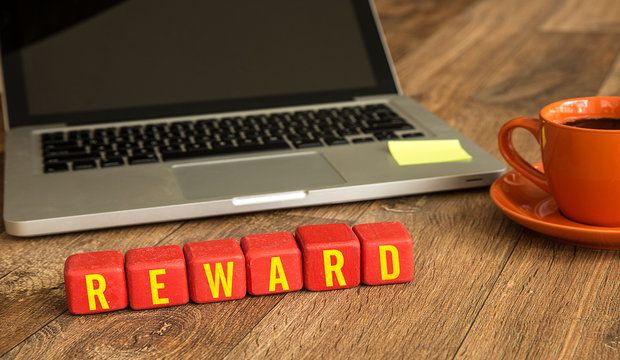 Reward written on a wooden cube in office desk