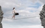 Young confident businesswoman walking on rope above gap