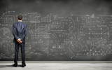 Business person standing against the blackboard with a lot of data written on it