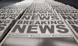 A long row of folded newspapers at the end of a press run with a generic headline that reads breaking news on the front page on an isolated white background