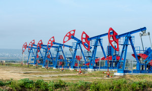 Oil and gas industry. Work of oil pump jack on a oil field. White clouds and blue sky. oil well pump. Oil and gas industry. Work of oil pump jack on a oil field.