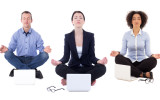 young business people sitting in yoga pose with laptops isolated on white background