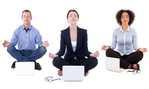 young business people sitting in yoga pose with laptops isolated on white background