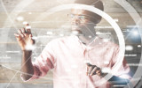 Visual effects. Future technology touch screen interface. High technology concept. Serious African American office worker using futuristic digital device pointing on sensor screen. Selective focus