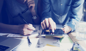Photo Woman Hand Touching Digital Tablet Screen.Analyst Department Researching Process.Young Business Crew Working New Startup modern Studio.Analyze markets stocks.Blurred, film effect.Wide