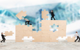 Team of businessmen collaborate and cooperate to build a puzzle