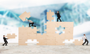 Team of businessmen collaborate and cooperate to build a puzzle
