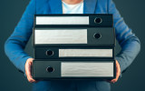 Accountant holding document binders with archived paperwork and other corporate legal sheets mock up copy space