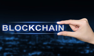 hand pushing blockchain button on blurred blue background