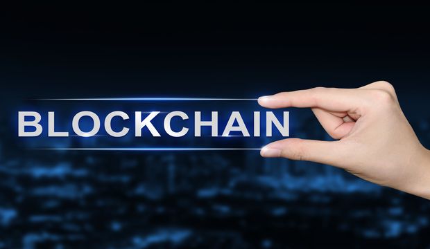 hand pushing blockchain button on blurred blue background
