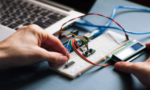 Microchip manual connecting to microcontroller. Top view on engeneer hands working with microcontroller. Closeup of microcontroller