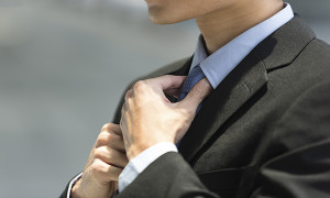 Close up detail of businessman adjusting his tie.