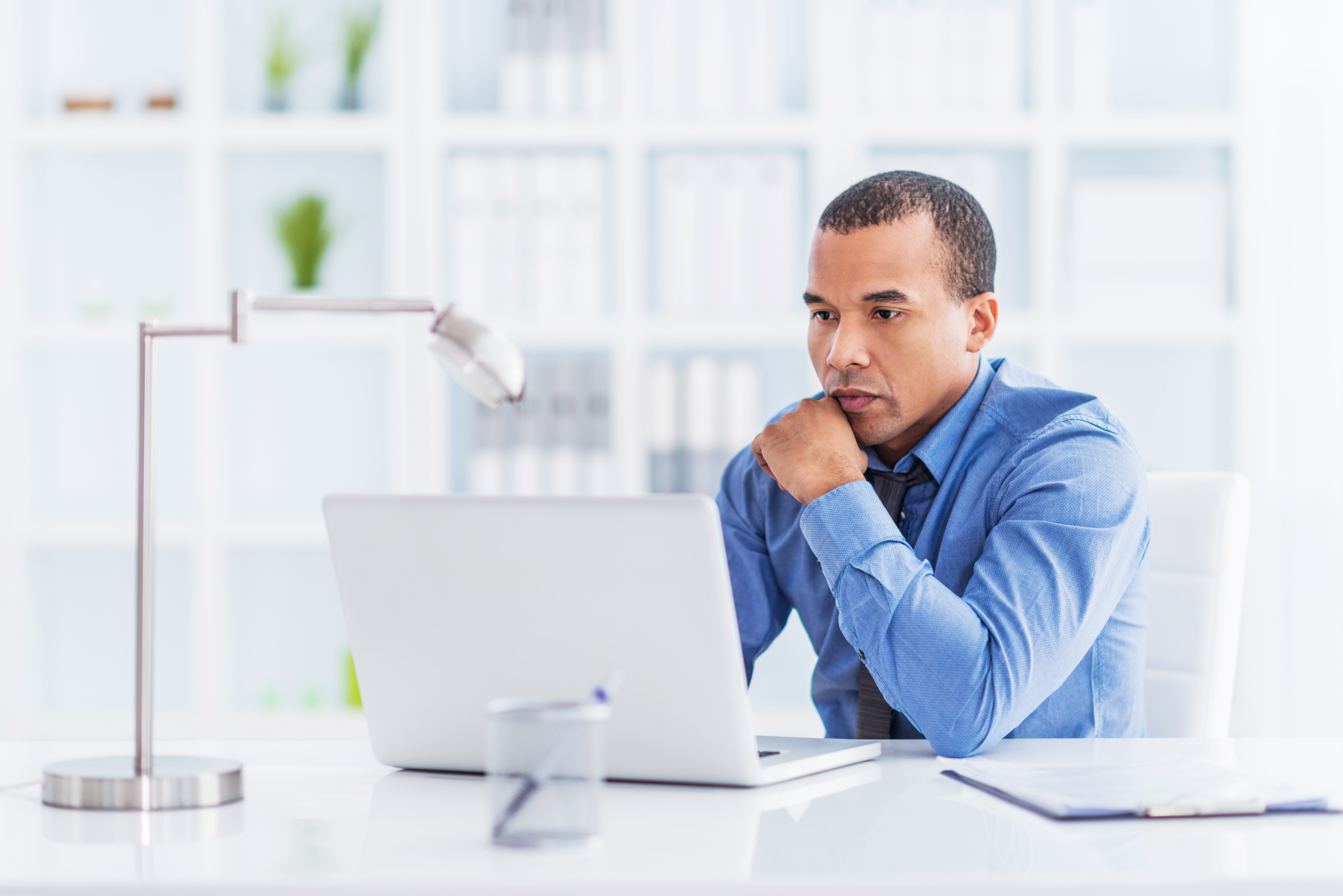 Serious African American businessman working on laptop in office.