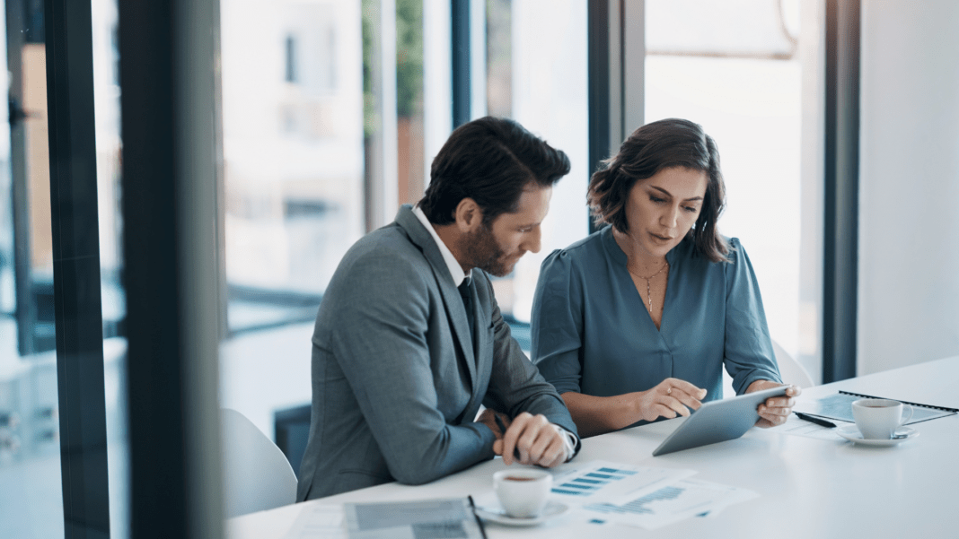 TIBCO Featured Blog Image Correct size Two business professionals engaged in discussion at a table, utilizing a tablet for collaboration and information sharing.