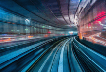 Blurred motion view of a cityscape from a moving train at night with vivid lights.