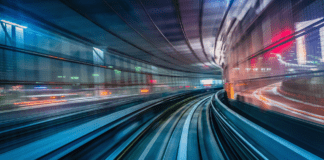 Blurred motion view of a cityscape from a moving train at night with vivid lights.