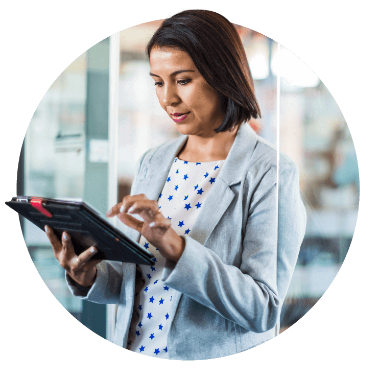 A woman in a blazer attentively using a tablet in a business environment