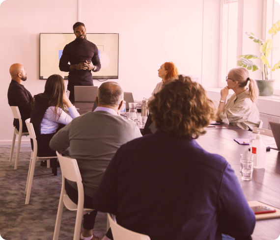 A group of people listening to a man in a meeting