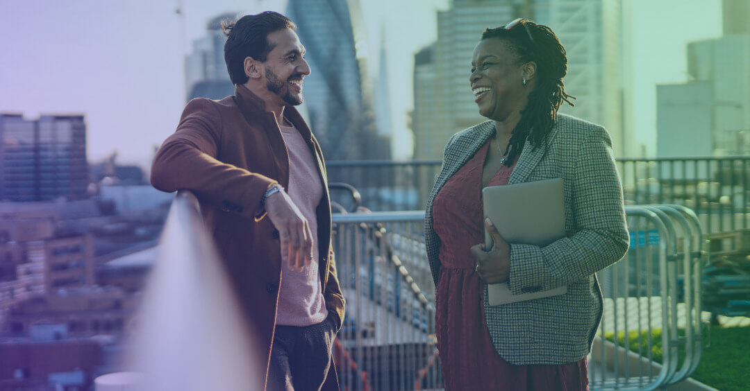 Two coworkers laugh on a workplace terrace