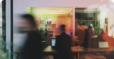 People walking inside an office space with desks